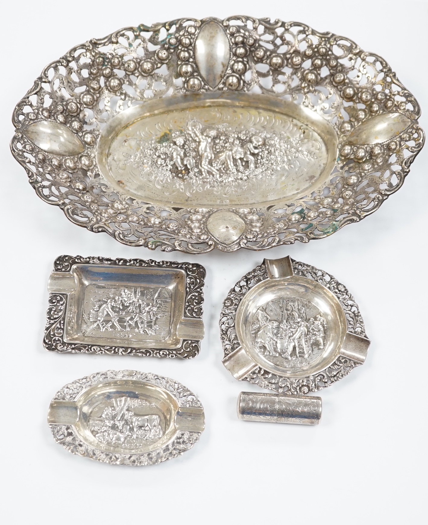A German pierced 800 white metal oval dish, 28.4cm, three Dutch white metal ashtrays and an 835 white metal lighter.